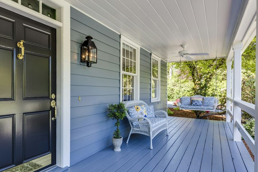 A covered front porch with a painted deck and a chair